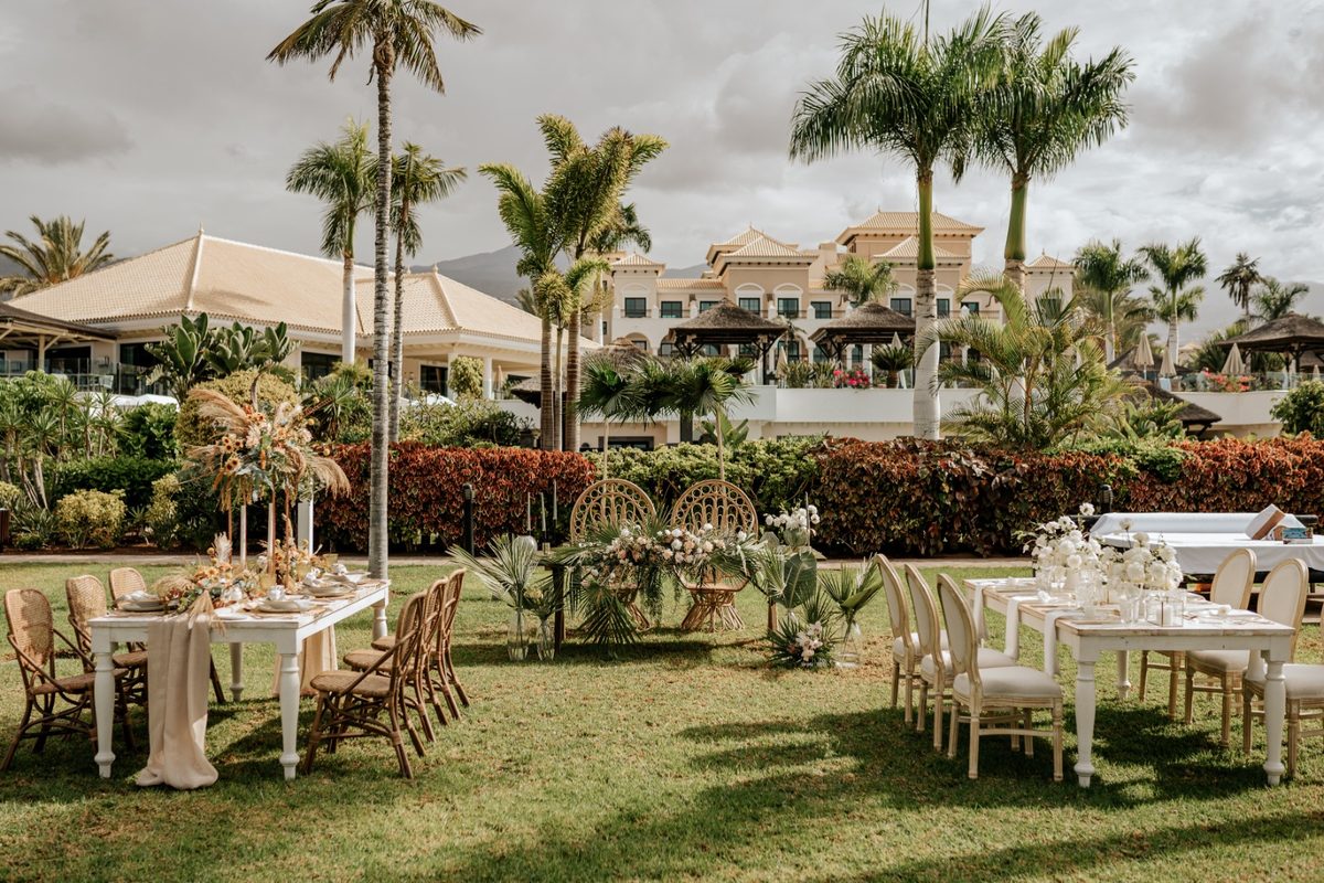 Outdoor wedding dinner tables on a garden lawn among palm trees