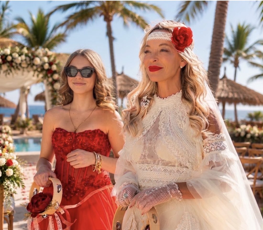 Bride with a red rose in her hair beside a guest in a red dress