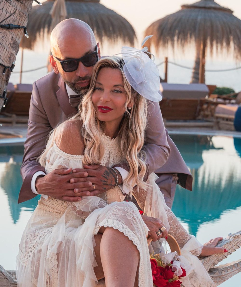 Bride and groom embracing on a poolside daybed